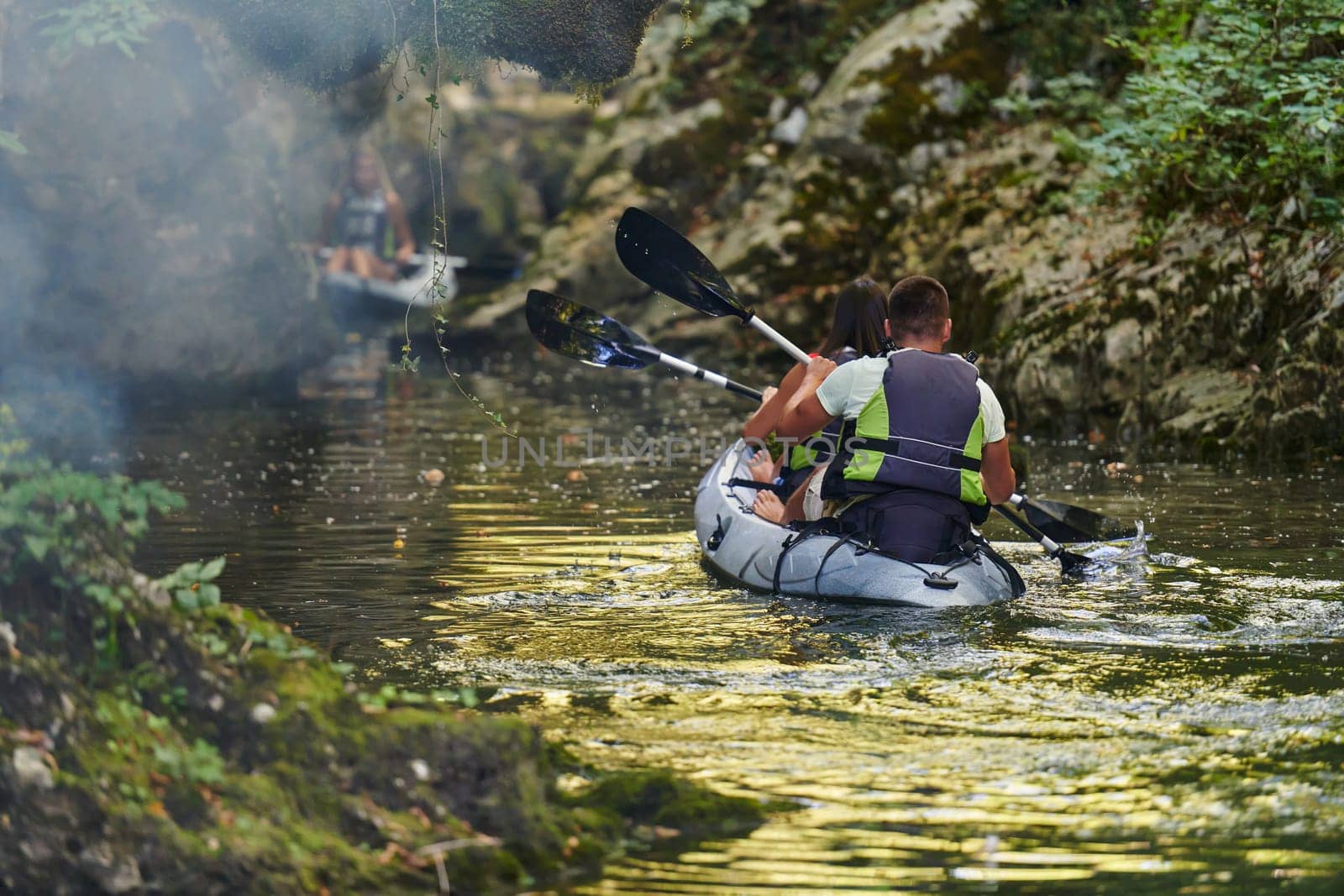 A group of friends enjoying having fun and kayaking while exploring the calm river, surrounding forest and large natural river canyons by dotshock