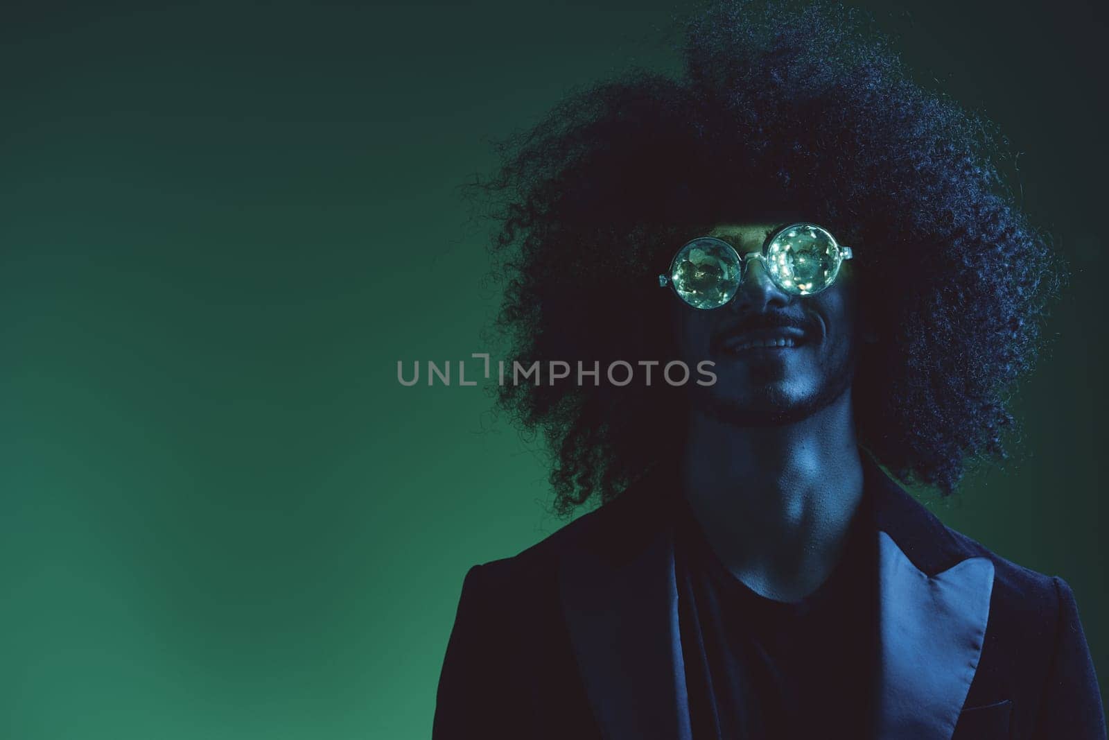 Fashion portrait of a man with curly hair on a green background with sunglasses, multinational, colored pink light, trendy, modern concept. by SHOTPRIME