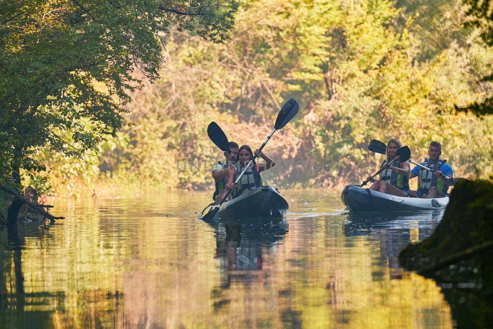 A group of friends enjoying having fun and kayaking while exploring the calm river, surrounding forest and large natural river canyons by dotshock