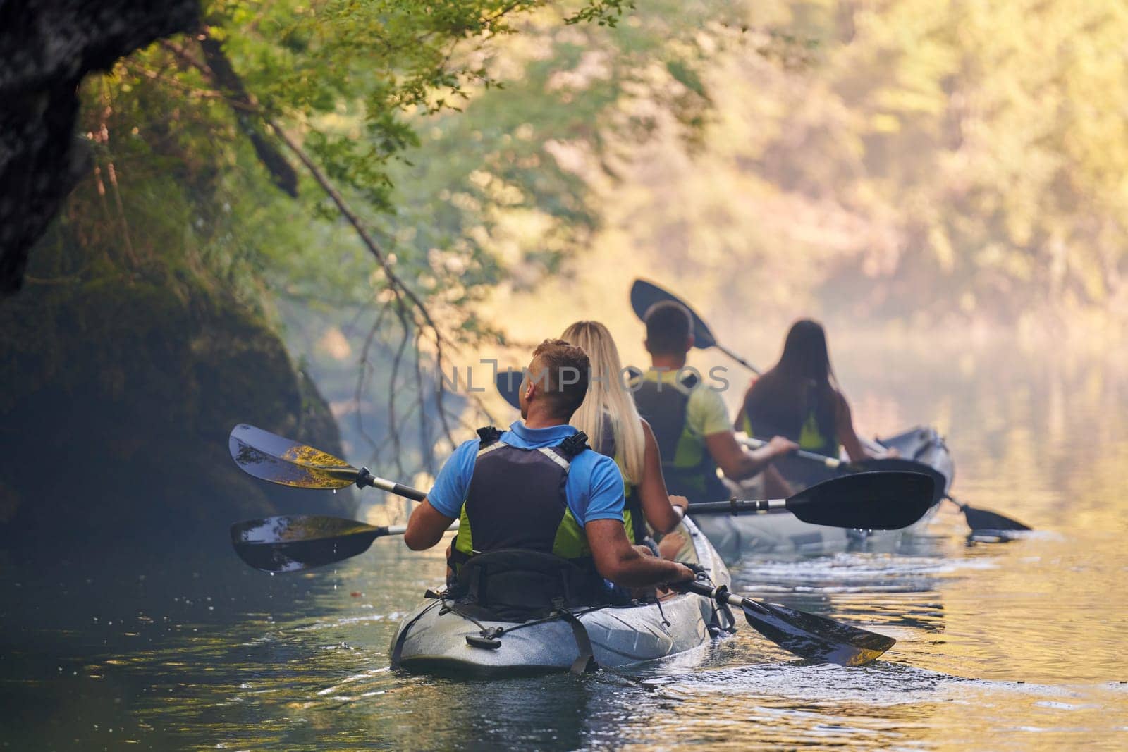 A group of friends enjoying having fun and kayaking while exploring the calm river, surrounding forest and large natural river canyons by dotshock