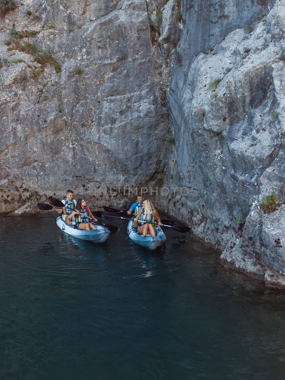 A group of friends enjoying fun and kayaking exploring the calm river, surrounding forest and large natural river canyons during an idyllic sunset