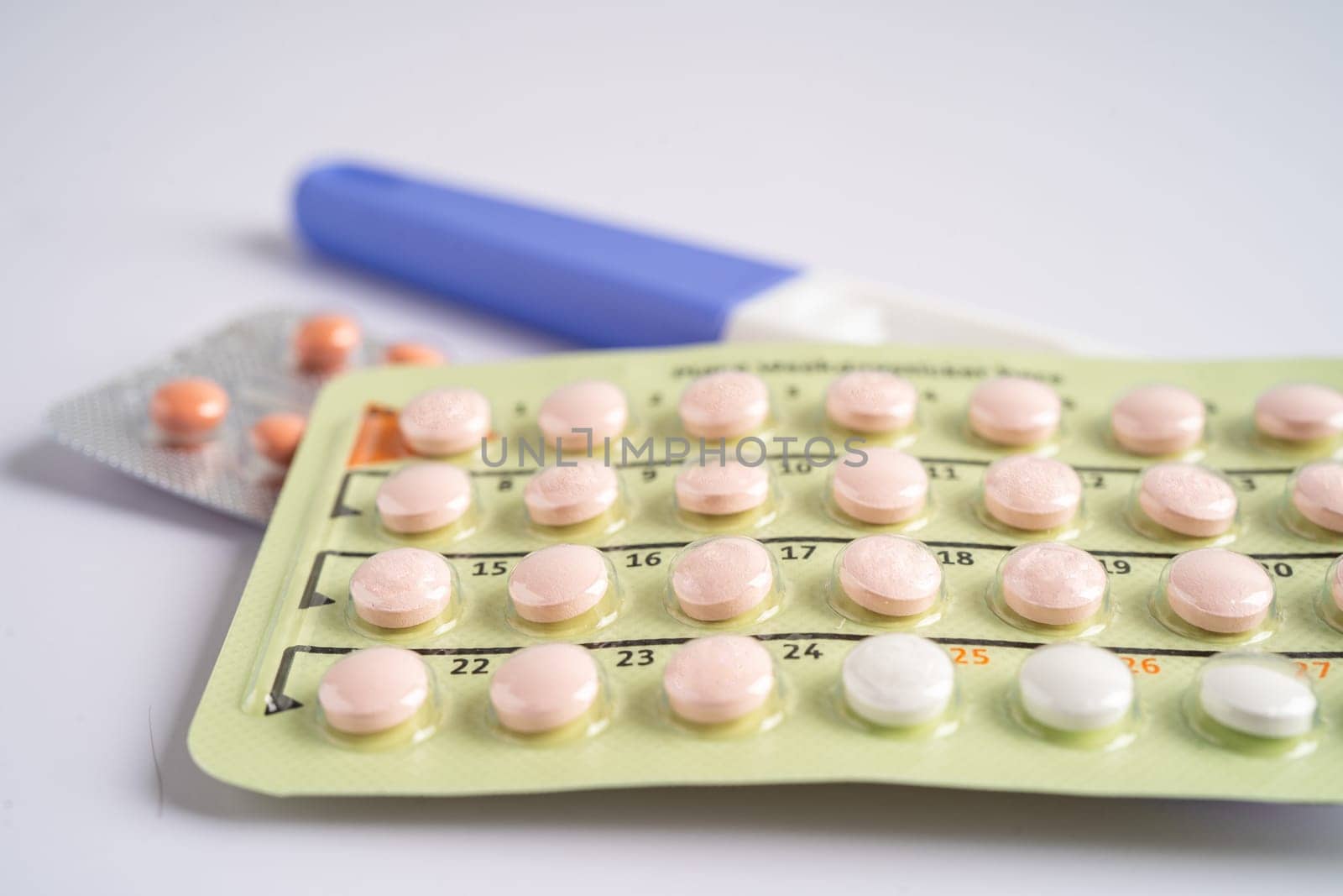 Pregnancy test and birth control pills on calendar, contraception health and medicine.