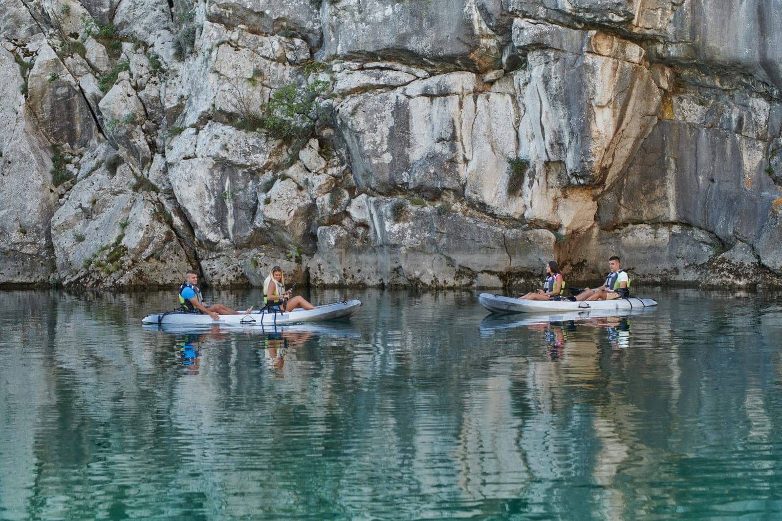 A group of friends enjoying having fun and kayaking while exploring the calm river, surrounding forest and large natural river canyons by dotshock