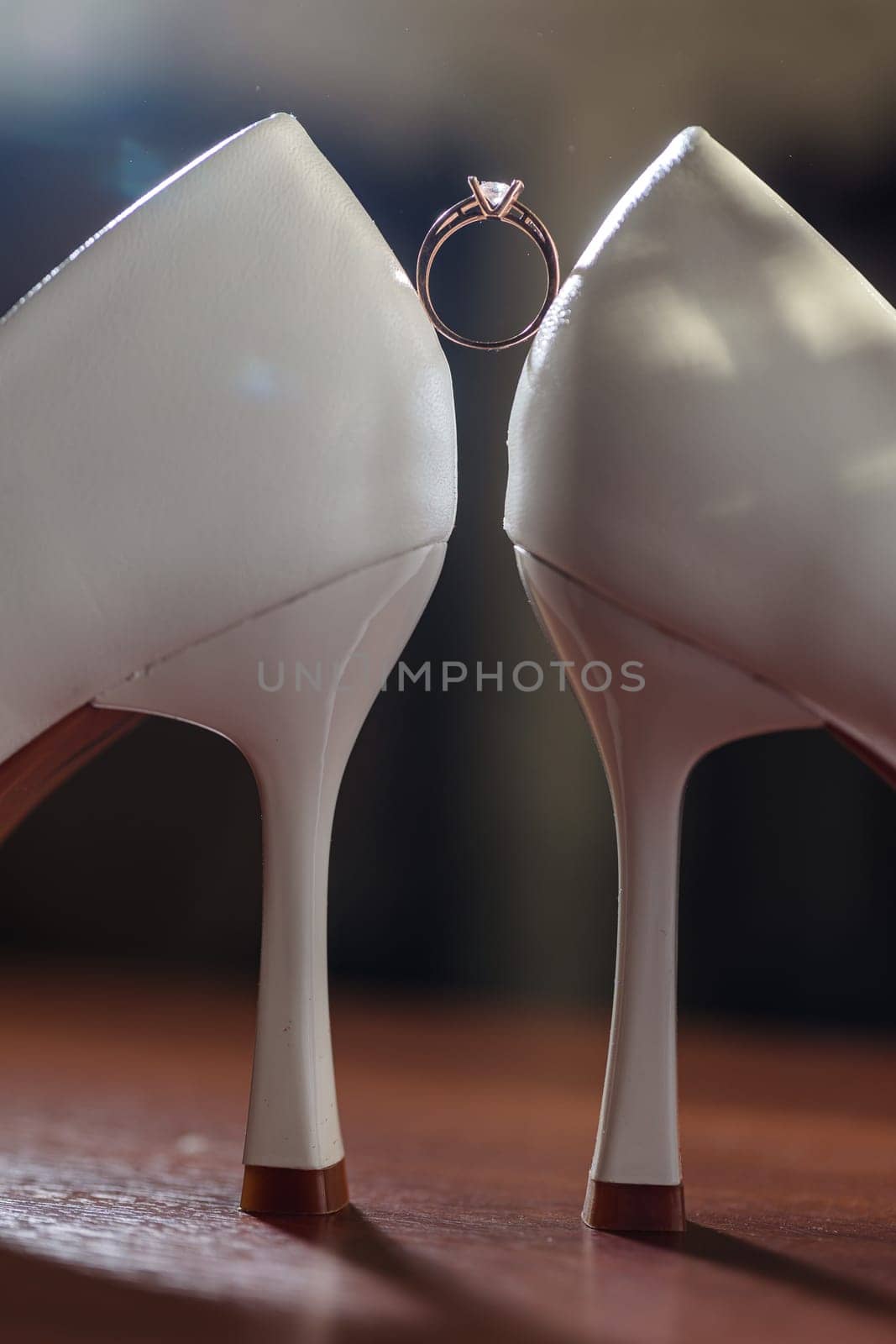 Gold ring of the bride with a pebble between white shoes with heels. Bride's precious ring by Dmitrytph
