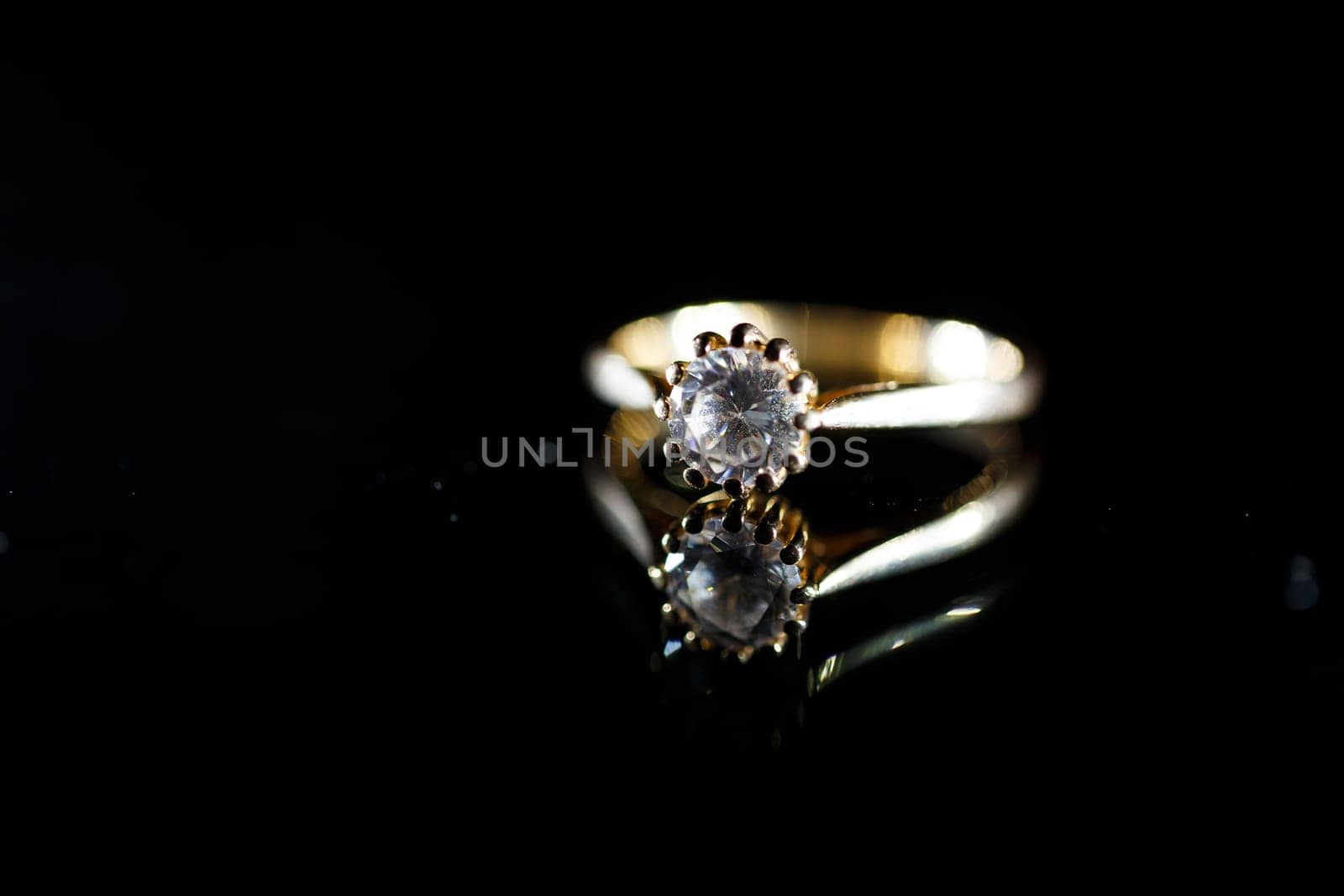 Gold wedding ring on black glass