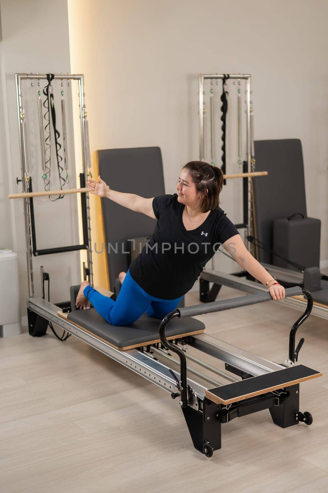 Overweight caucasian woman doing pilates exercises on a reformer