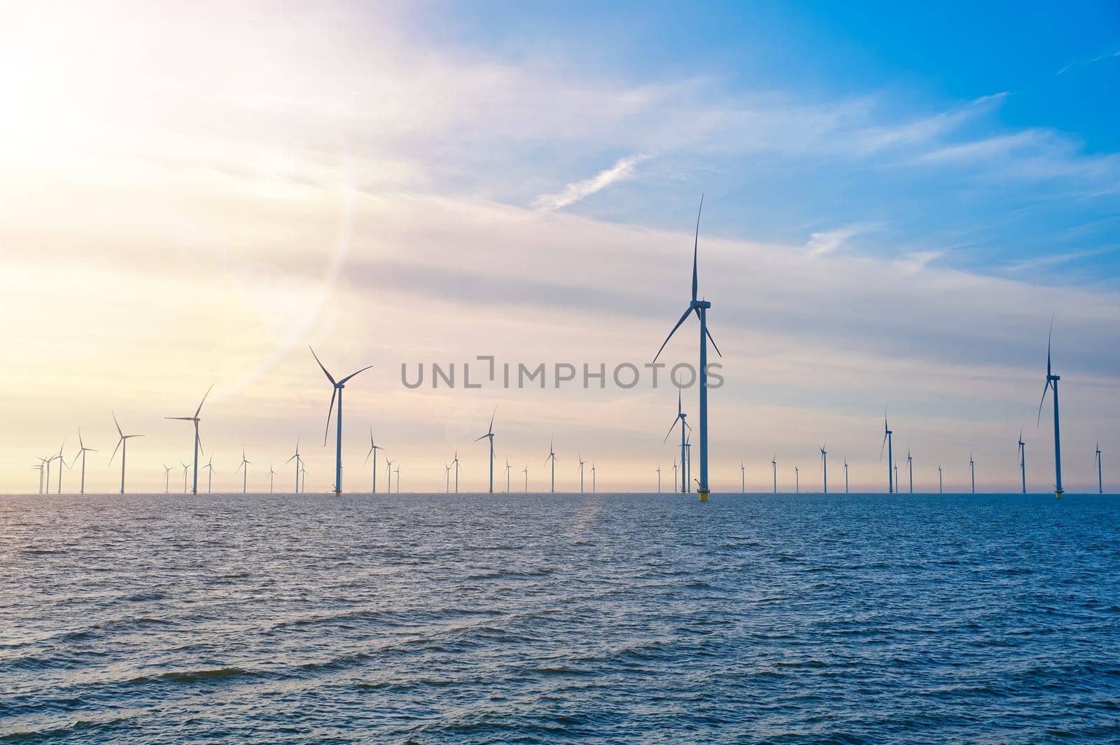 Offshore Windmill farm. windmills isolated at sea on a beautiful bright day Netherlands. green energy Flevoland global warming renewable enrgy with windmills