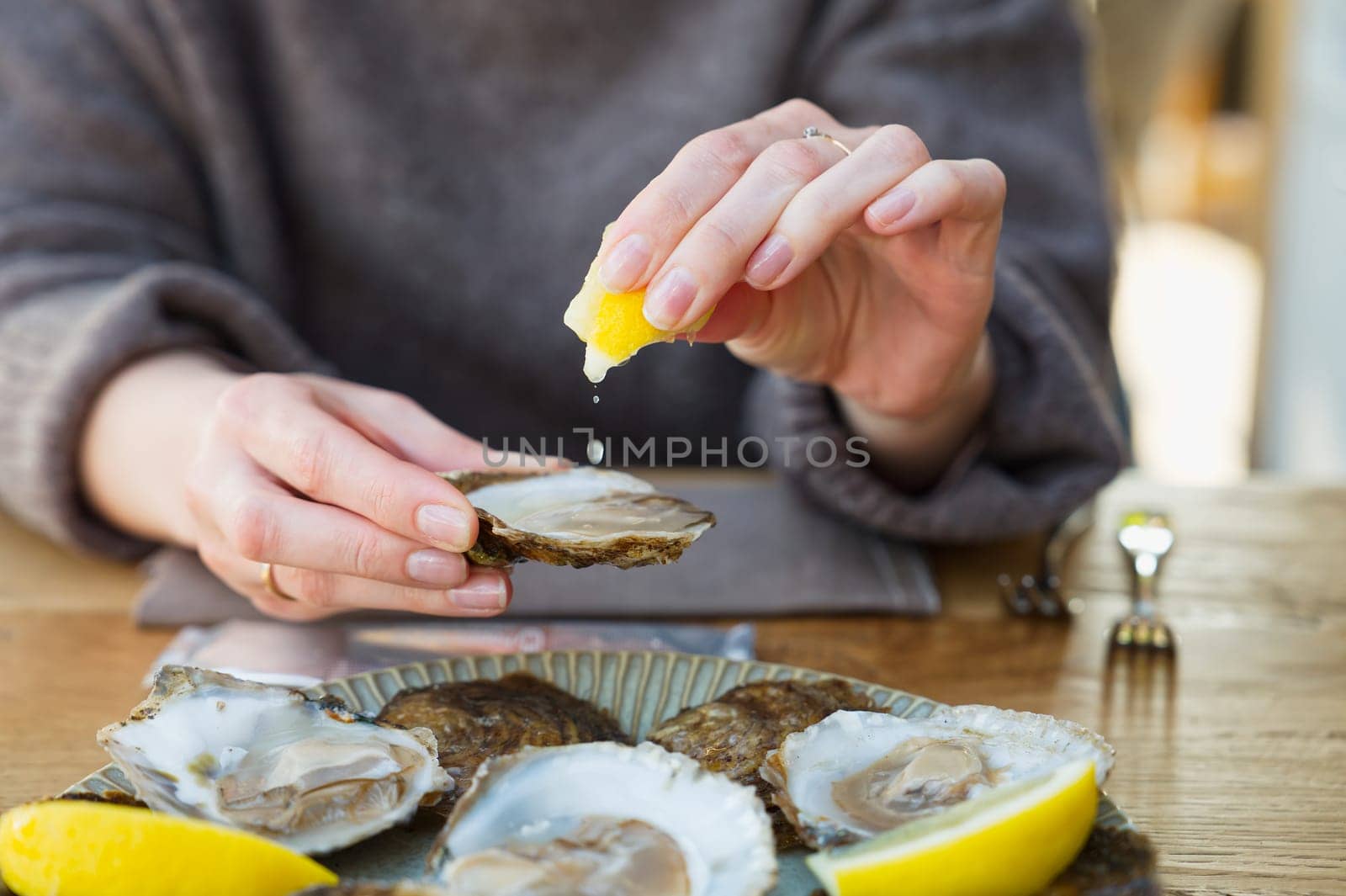 Beautiful Woman eating fresh oysters and drinking in restaurant. Seafood delicacies. by PhotoTime