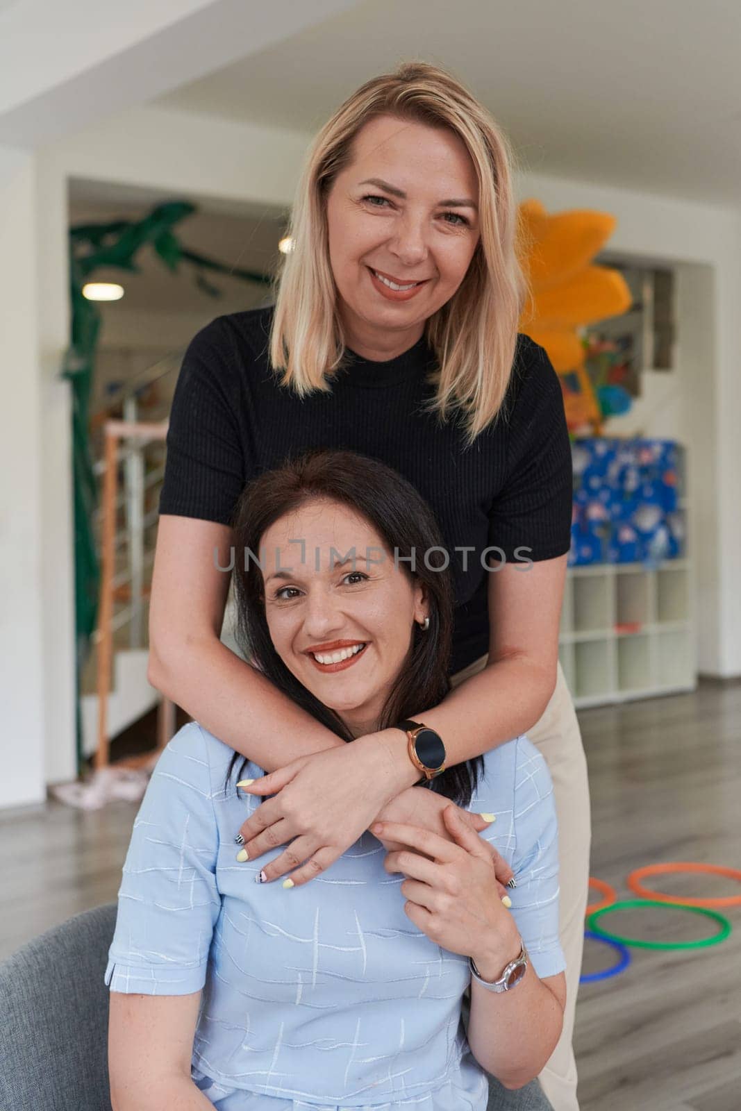 Two women share a heartfelt embrace while at a preschool, showcasing the nurturing and supportive environment for learning and growth.