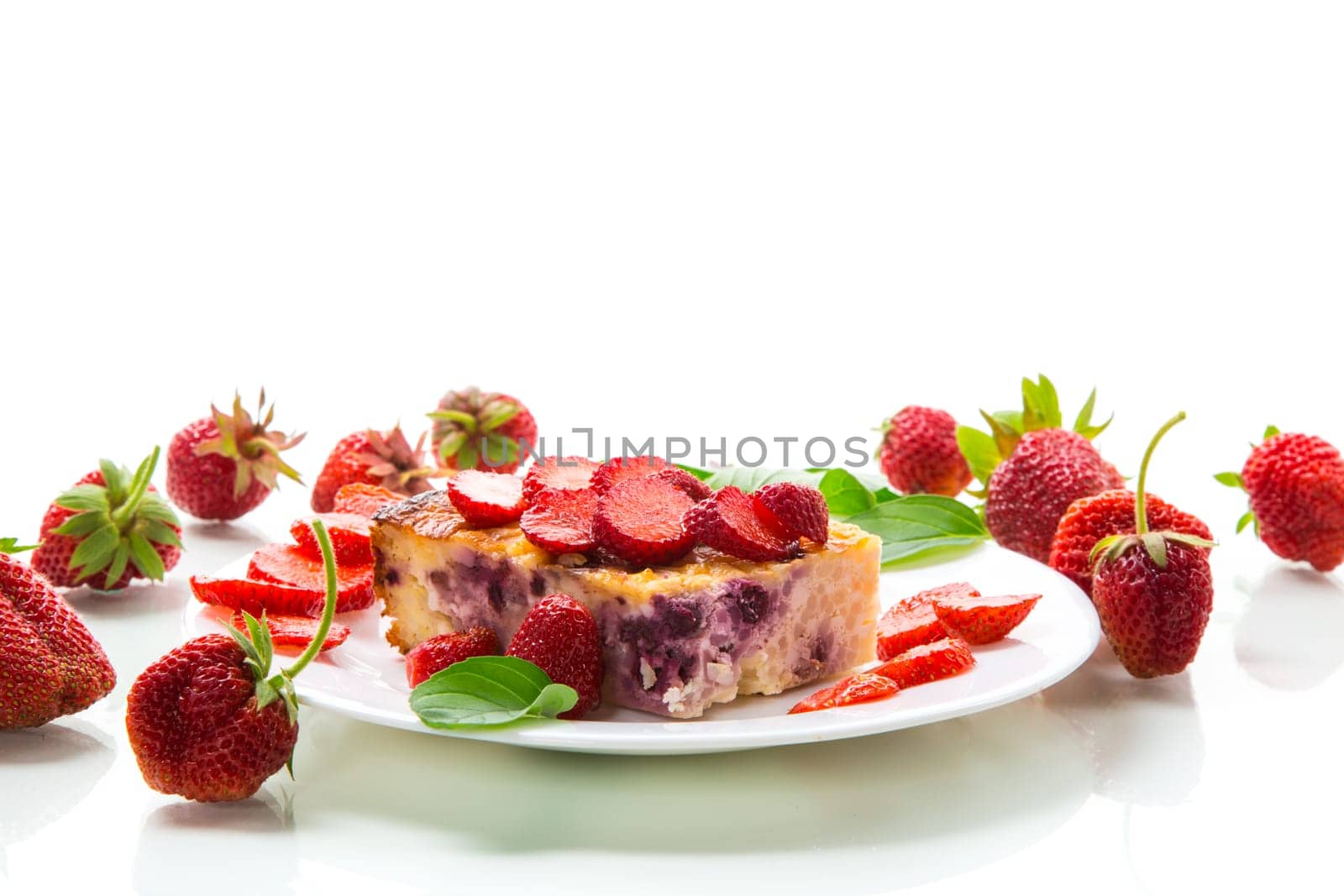 cooked cottage cheese casserole with berry and strawberry filling in a plate, isolated on white background.