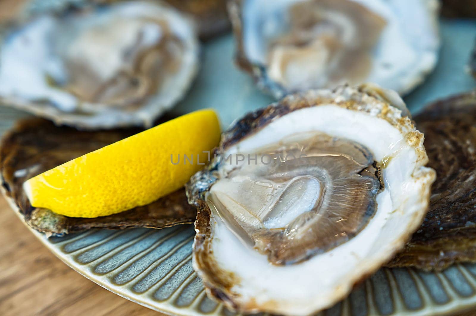 Fresh oysters served on a plate with lemon on old wooden table. Teasty Oysters served in fish restaurant.