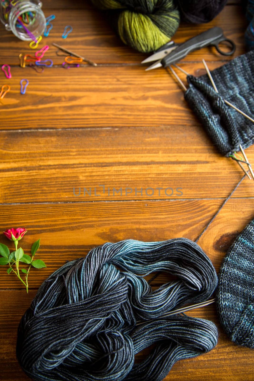 Set for hand knitting warm winter socks made of natural woolen yarn, on a wooden table.