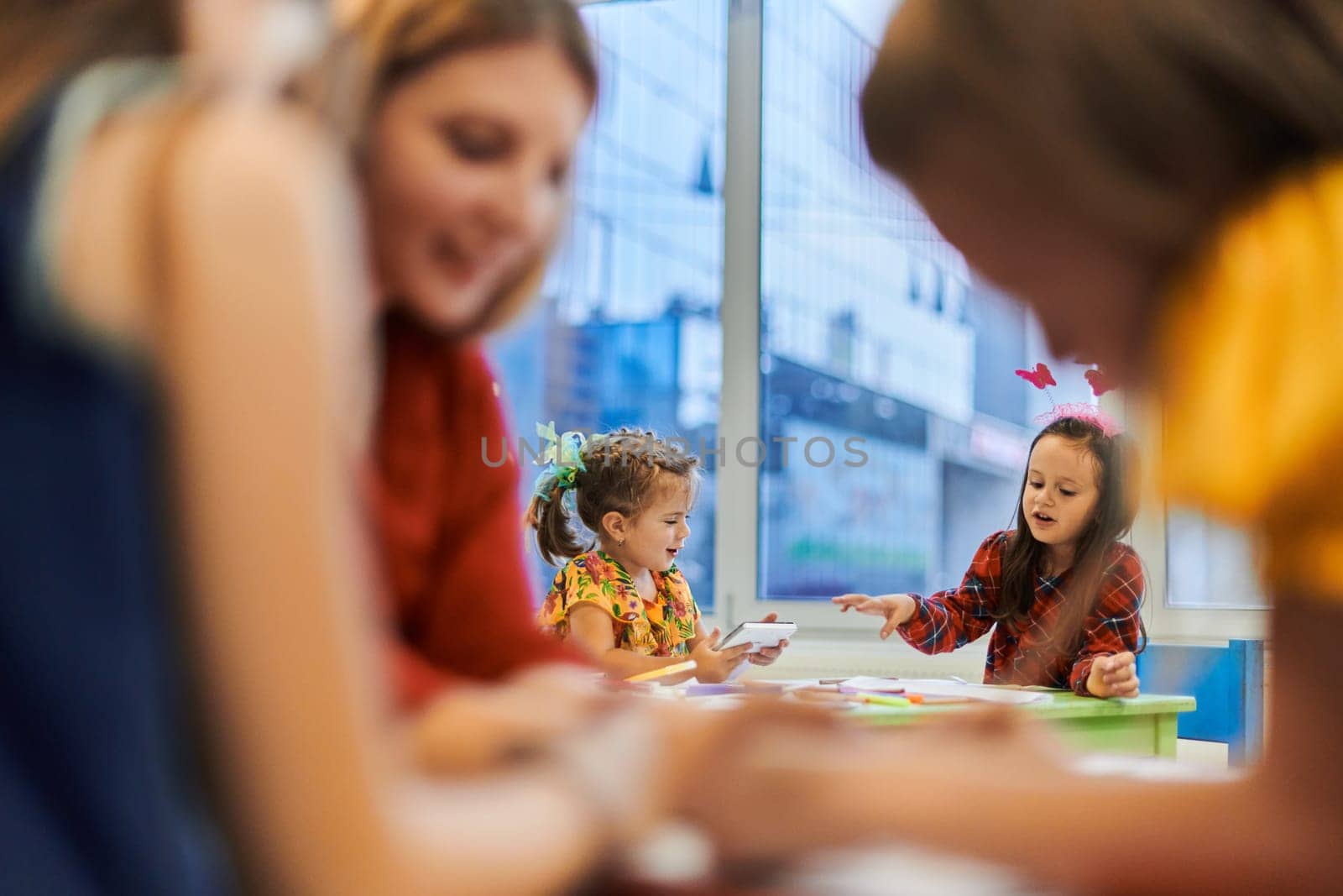 Creative kids during an art class in a daycare center or elementary school classroom drawing with female teacher. by dotshock