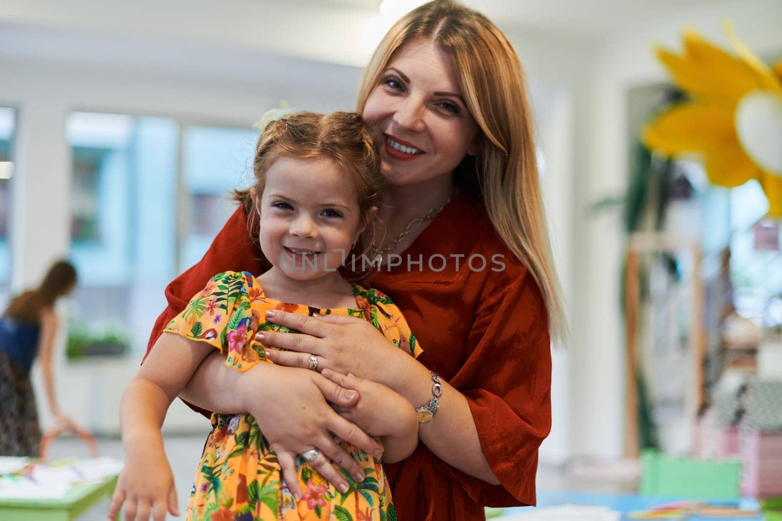 A cute little girl kissing and hugs her mother in preschool. High quality photo