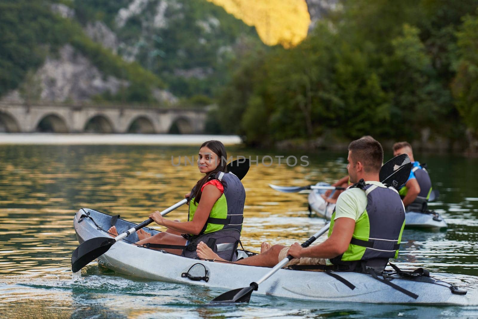 A group of friends enjoying having fun and kayaking while exploring the calm river, surrounding forest and large natural river canyons.