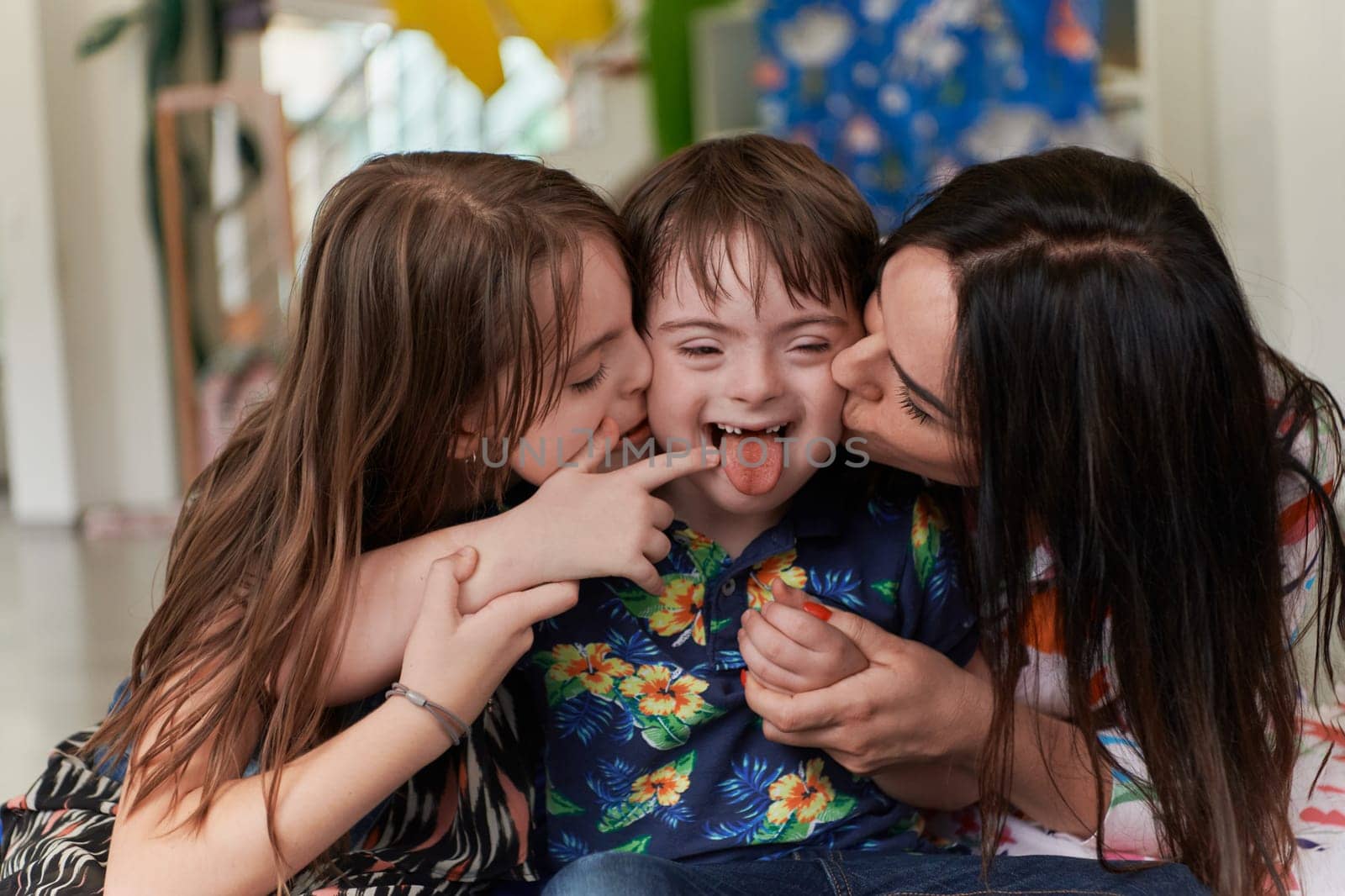 A girl and a woman hug a child with down syndrome in a modern preschool institution by dotshock