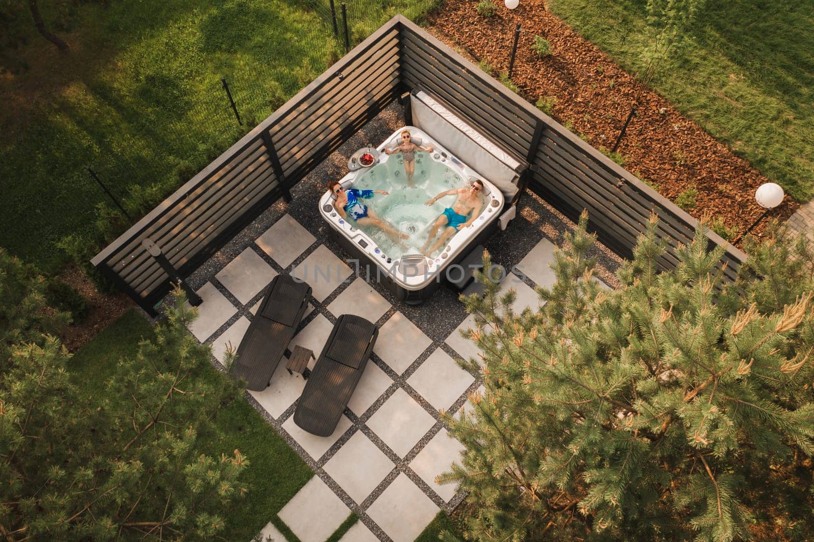 Top view of a family relaxing in an outdoor hot tub in summer by Lobachad