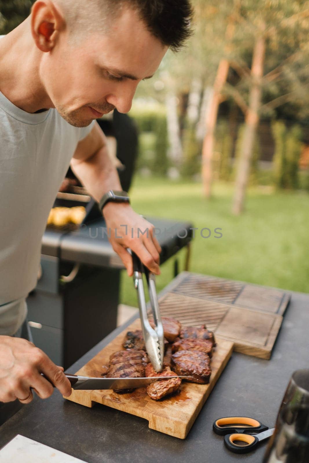 A man on the street cooked a steak on the grill in a barbecue.