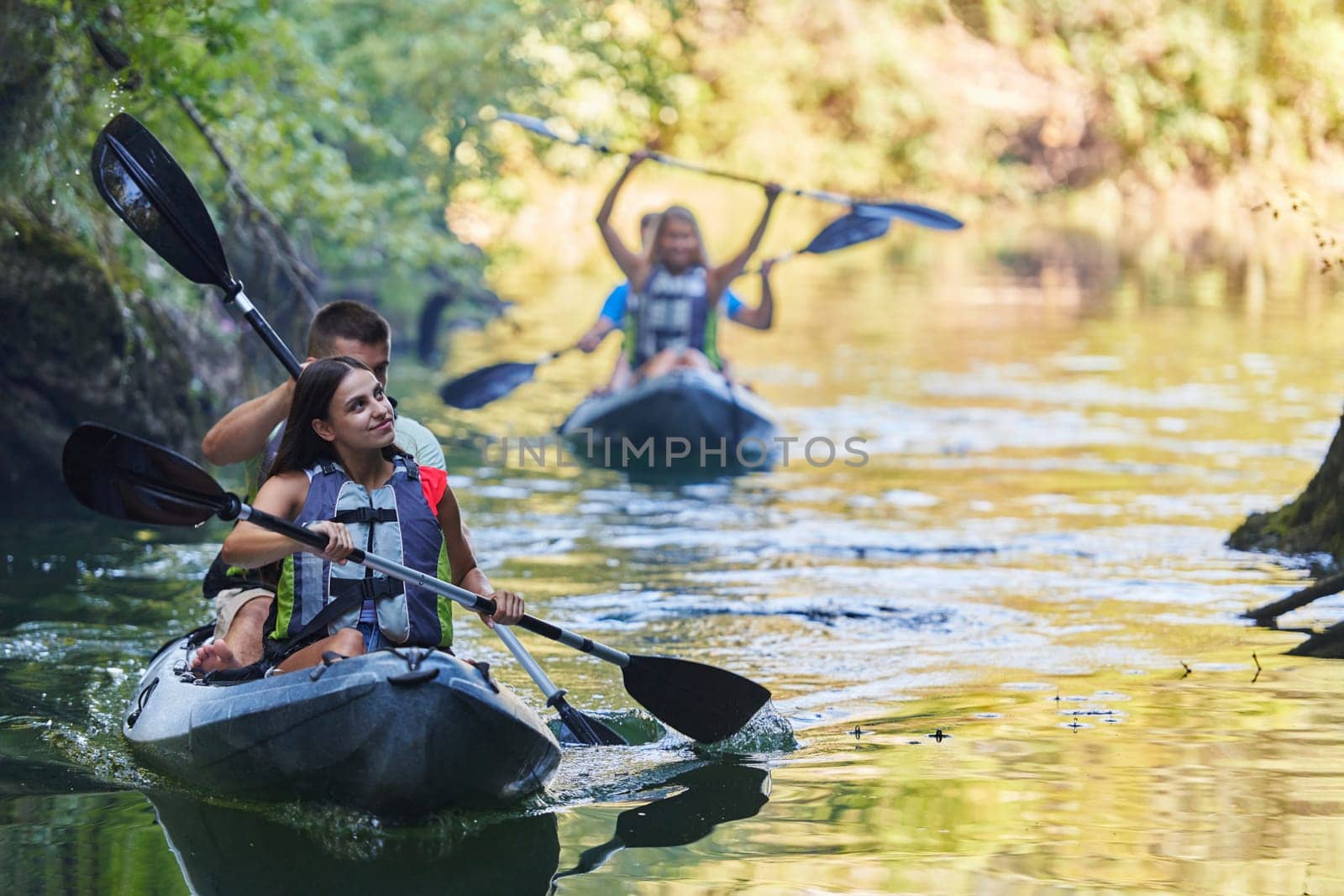 A group of friends enjoying having fun and kayaking while exploring the calm river, surrounding forest and large natural river canyons by dotshock