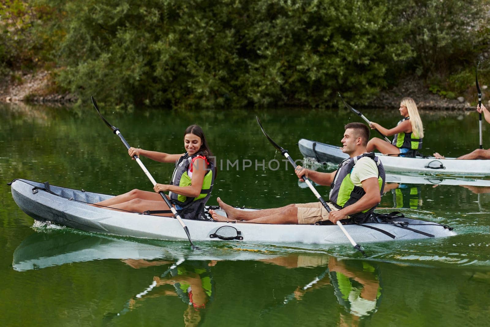 A group of friends enjoying having fun and kayaking while exploring the calm river, surrounding forest and large natural river canyons by dotshock