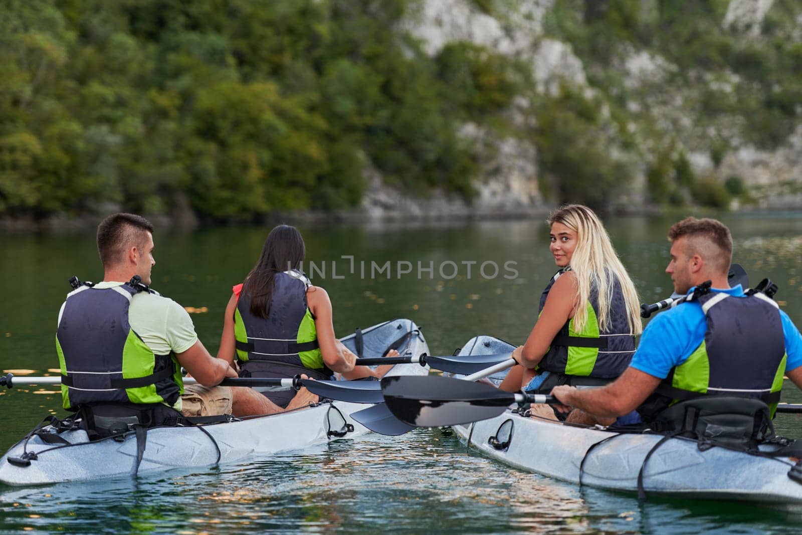 A group of friends enjoying having fun and kayaking while exploring the calm river, surrounding forest and large natural river canyons by dotshock