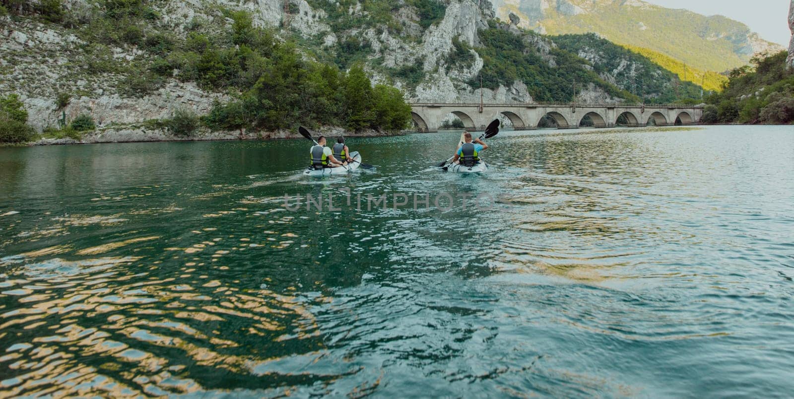 A group of friends enjoying having fun and kayaking while exploring the calm river, surrounding forest and large natural river canyons by dotshock