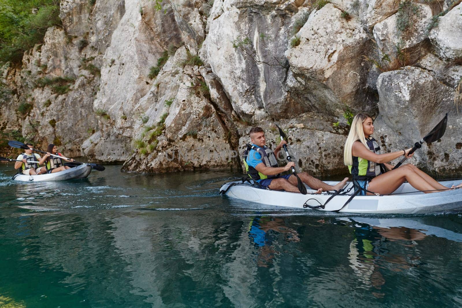 A group of friends enjoying having fun and kayaking while exploring the calm river, surrounding forest and large natural river canyons by dotshock