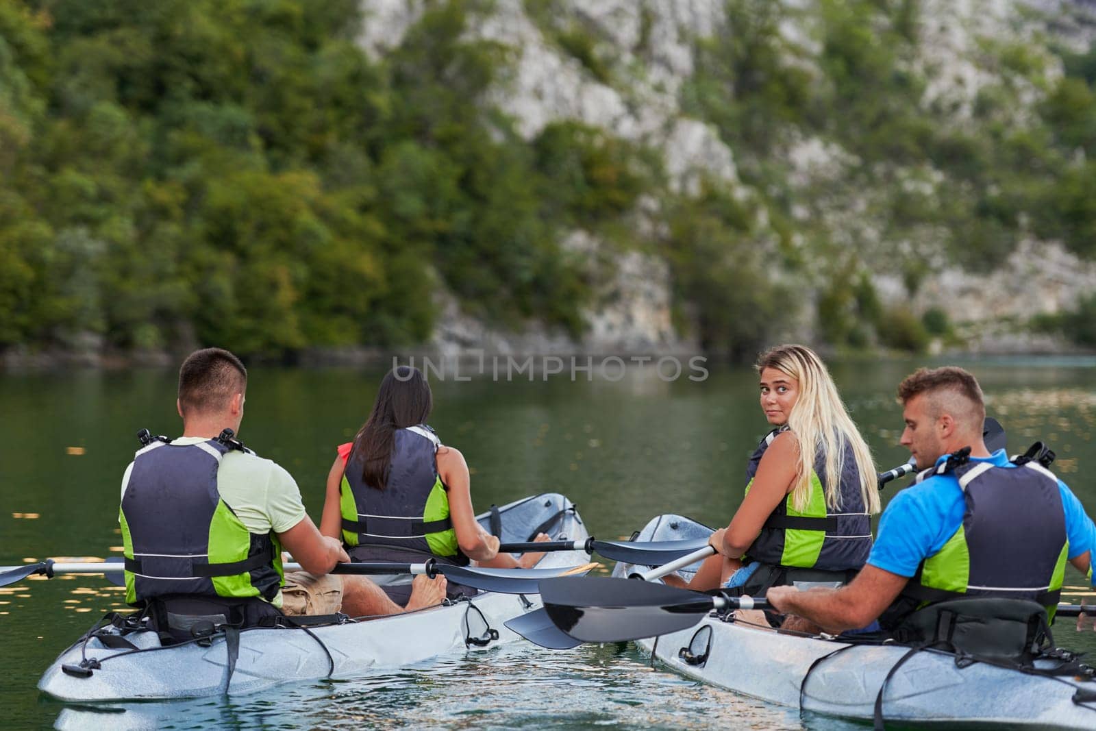 A group of friends enjoying having fun and kayaking while exploring the calm river, surrounding forest and large natural river canyons by dotshock