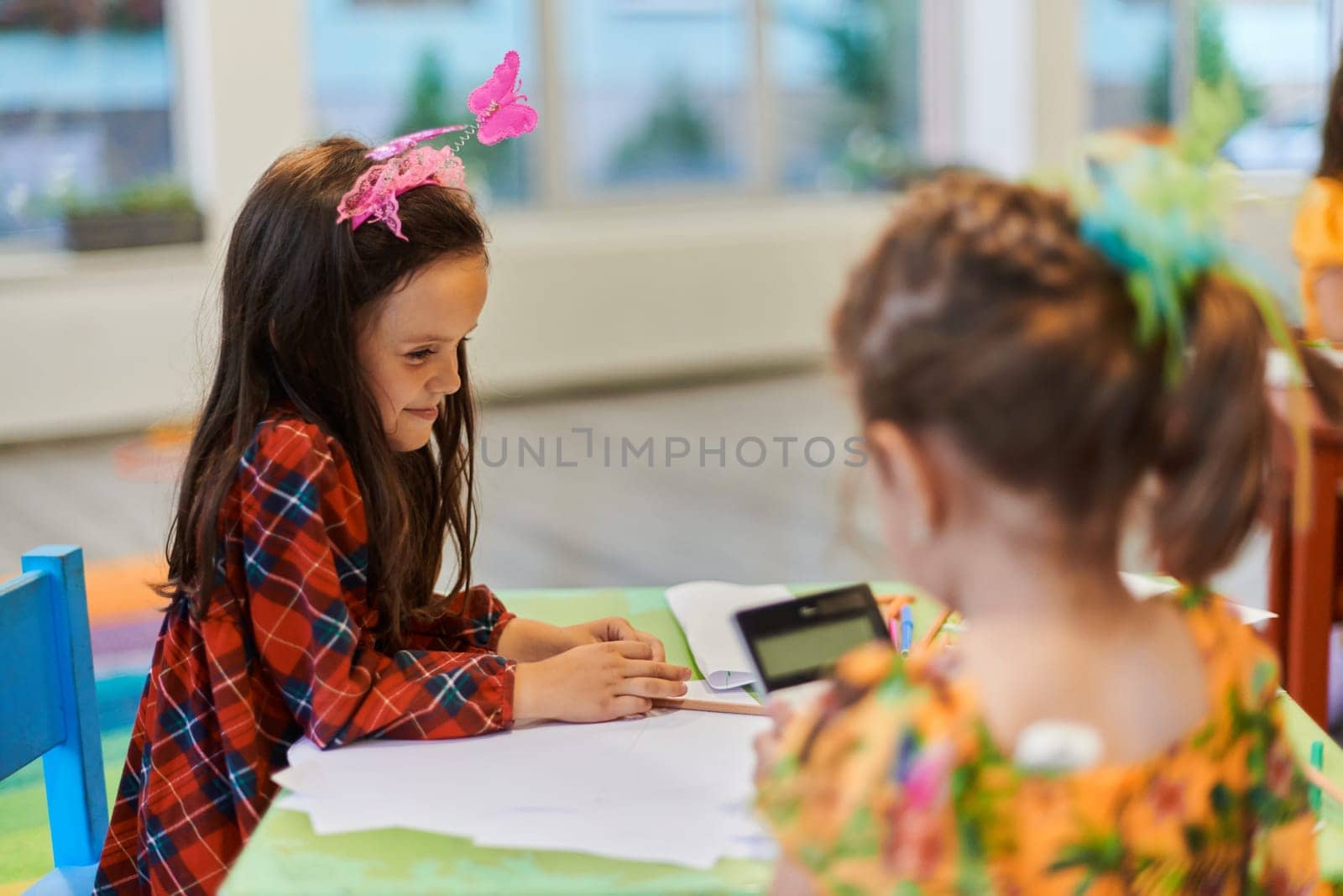 Creative kids during an art class in a daycare center or elementary school classroom drawing with female teacher