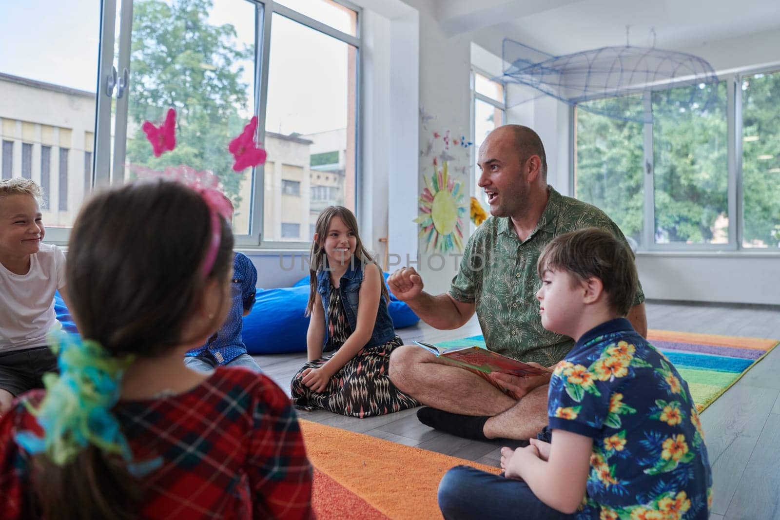 Reading time in an elementary school or kindergarten, a teacher reading a book to children in an elementary school or kindergarten. The concept of pre-school education. Selective focus by dotshock