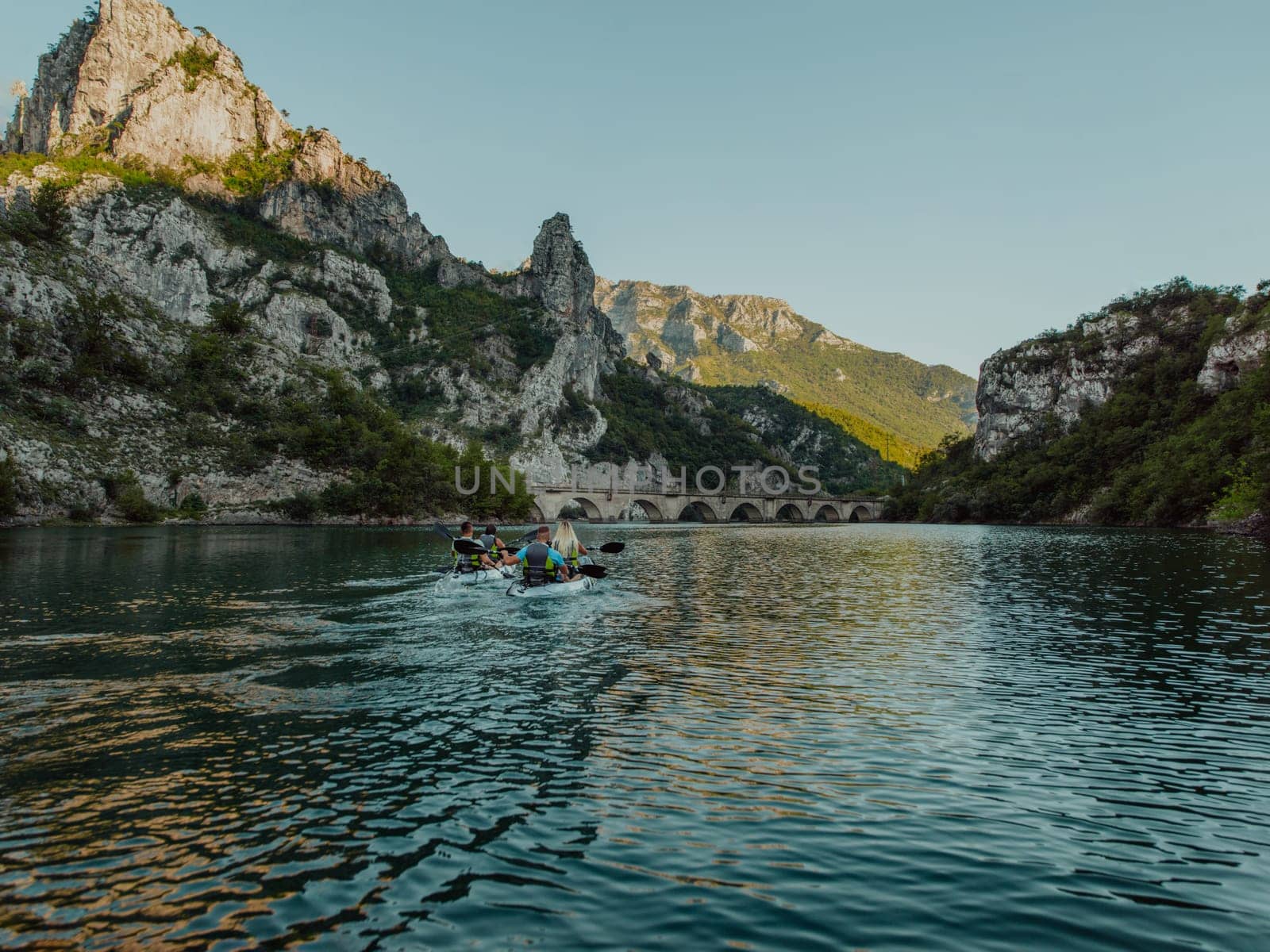 A group of friends enjoying having fun and kayaking while exploring the calm river, surrounding forest and large natural river canyons by dotshock