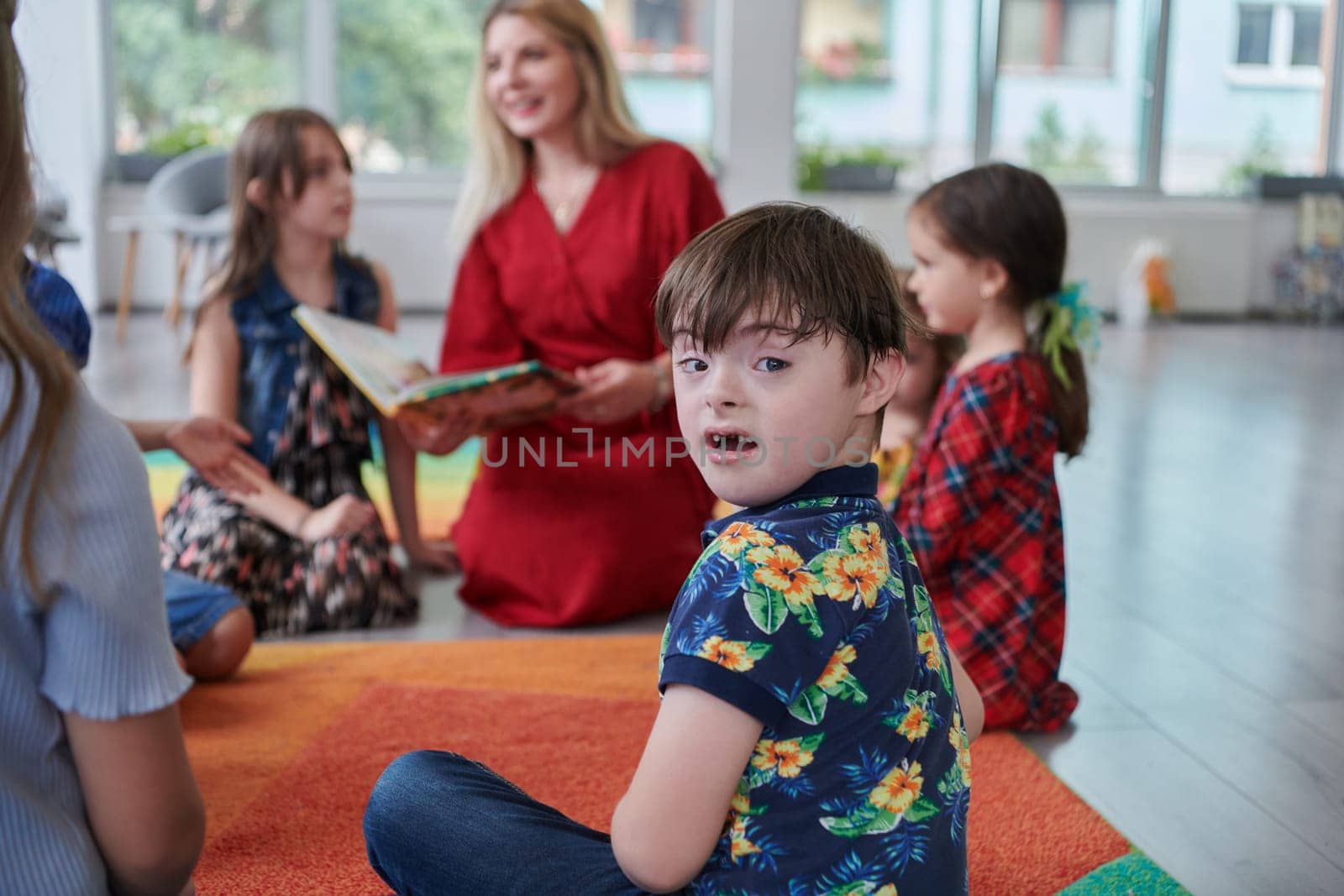 Reading time in an elementary school or kindergarten, a teacher reading a book to children in an elementary school or kindergarten. The concept of pre-school education. Selective focus by dotshock