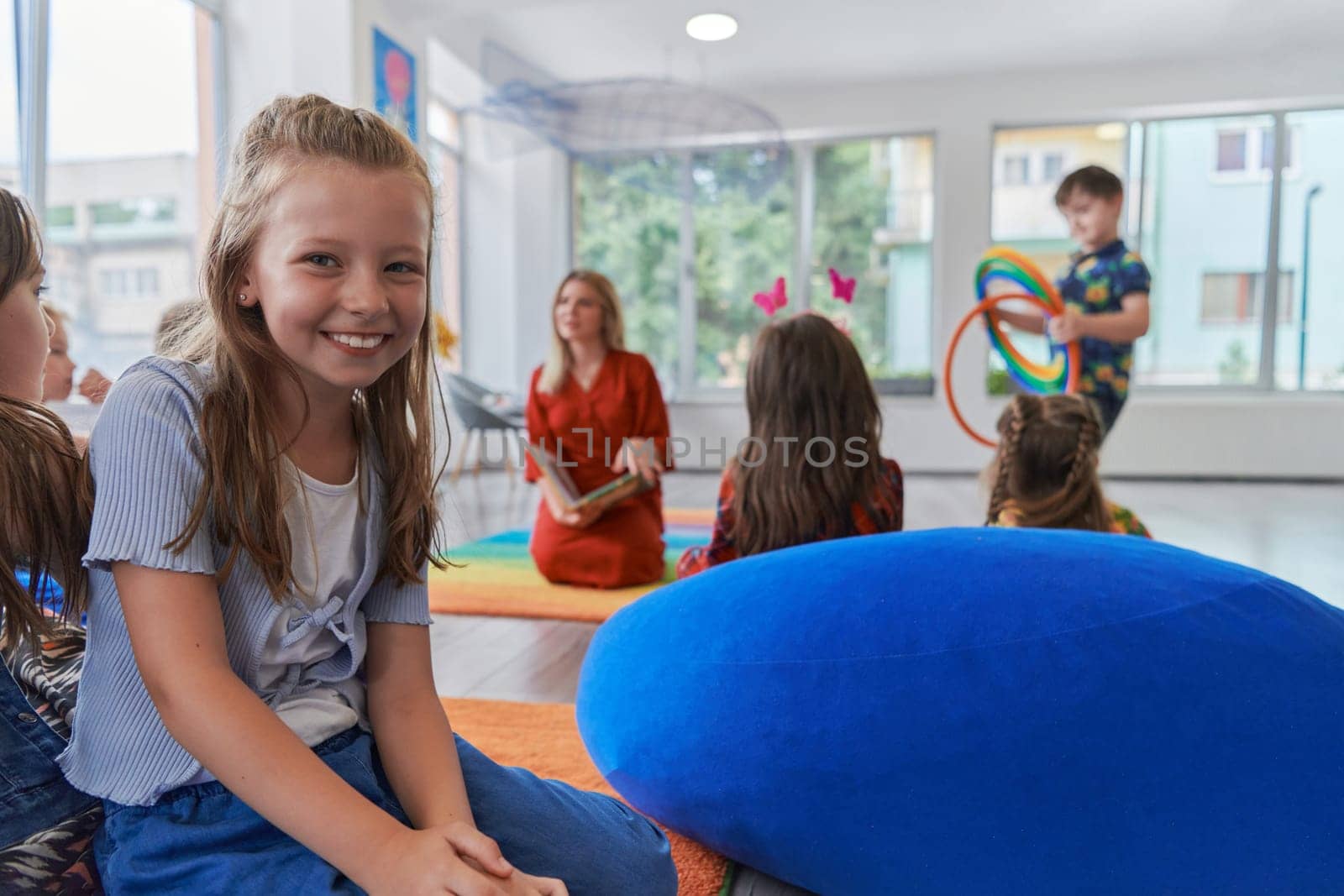 Reading time in an elementary school or kindergarten, a teacher reading a book to children in an elementary school or kindergarten. The concept of pre-school education. Selective focus by dotshock