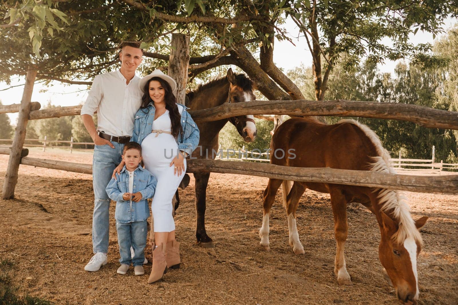 Happy family near horses at a farmer's ranch at sunset.