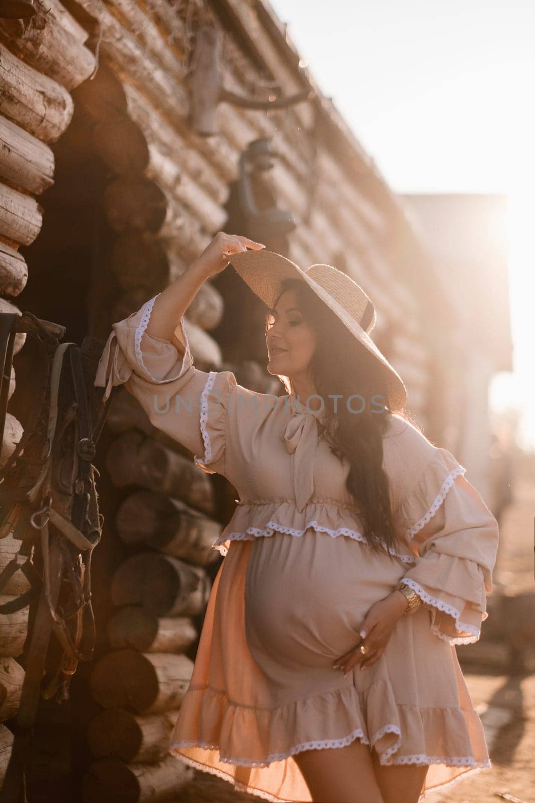 pregnant woman in a dress and hat in the countryside.