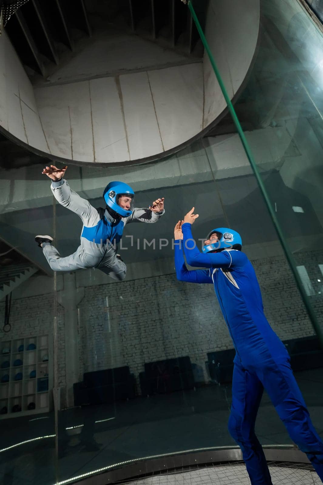 A male instructor teaches a woman how to fly in a wind tunnel. Free fall simulator