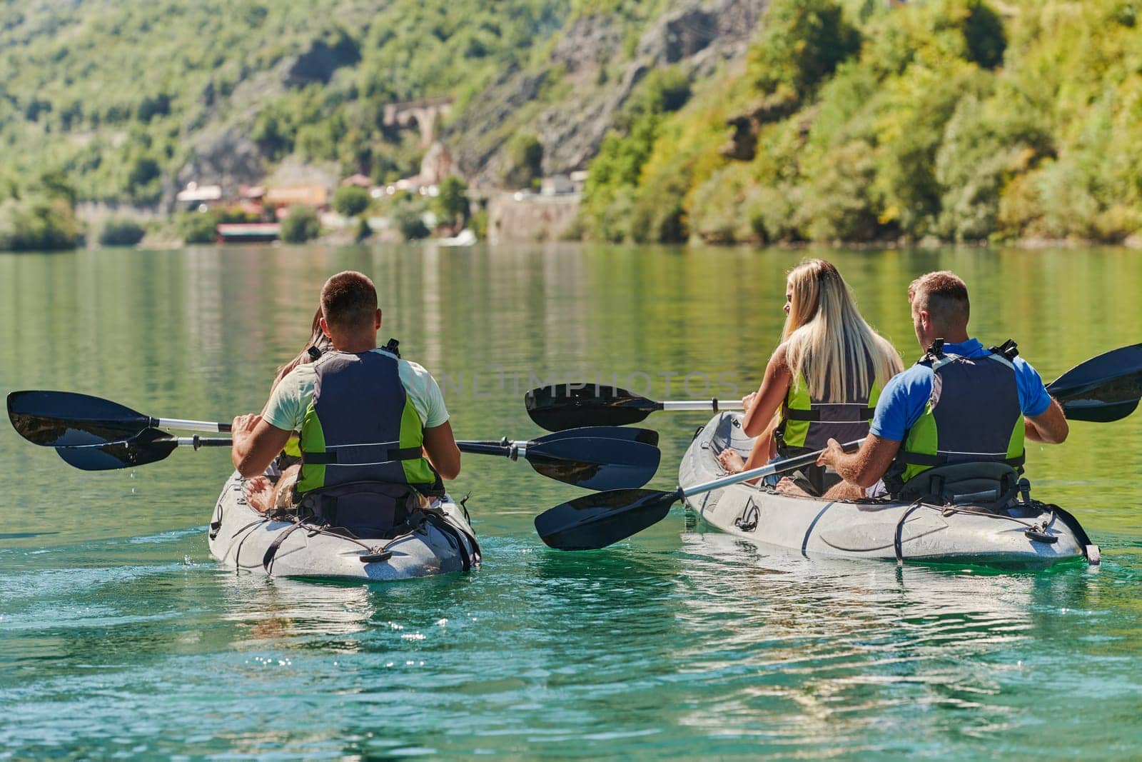 A group of friends enjoying having fun and kayaking while exploring the calm river, surrounding forest and large natural river canyons.