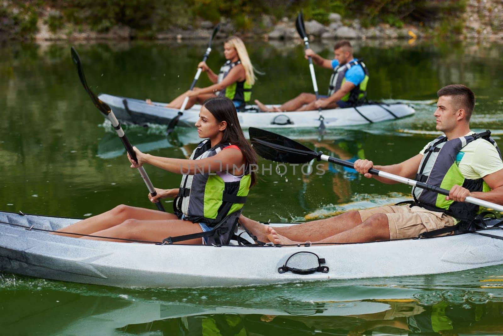 A group of friends enjoying having fun and kayaking while exploring the calm river, surrounding forest and large natural river canyons by dotshock