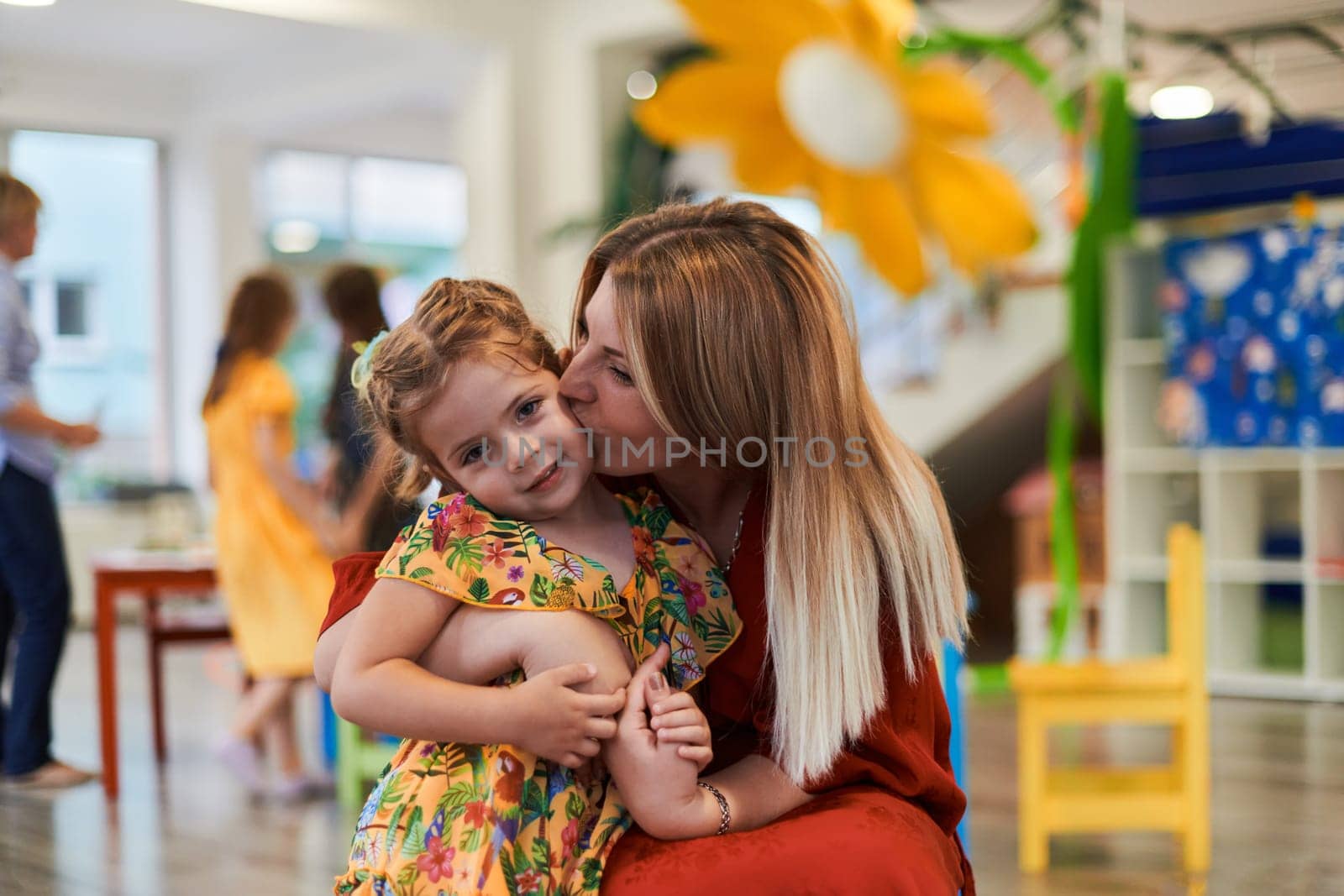 A cute little girl kissing and hugs her mother in preschool. High quality photo