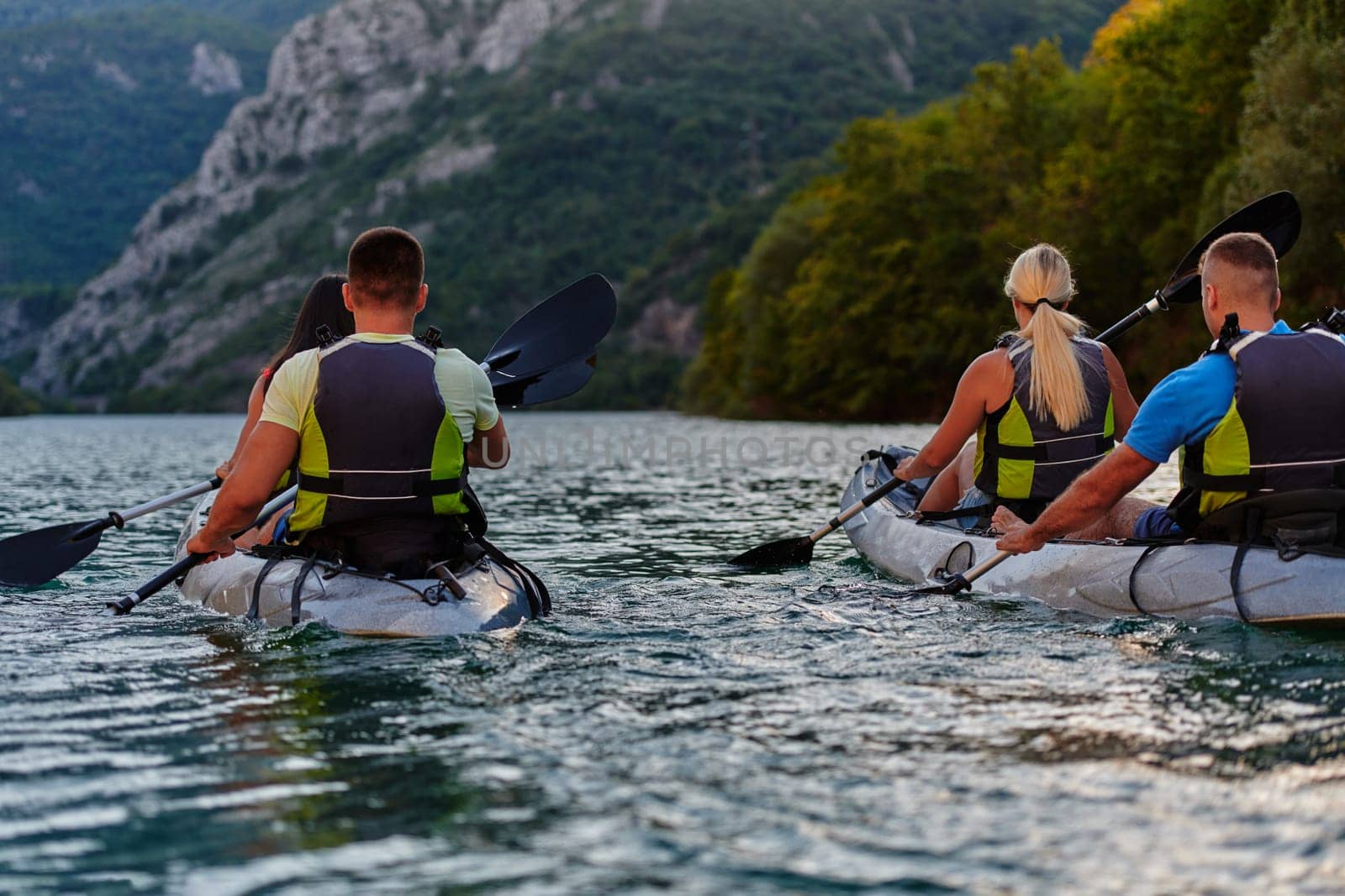 A group of friends enjoying having fun and kayaking while exploring the calm river, surrounding forest and large natural river canyons by dotshock