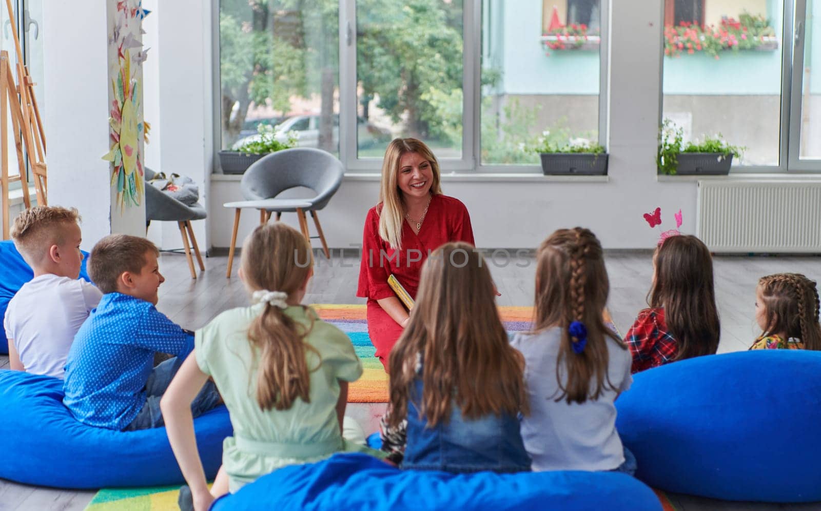 Reading time in an elementary school or kindergarten, a teacher reading a book to children in an elementary school or kindergarten. The concept of pre-school education. Selective focus by dotshock