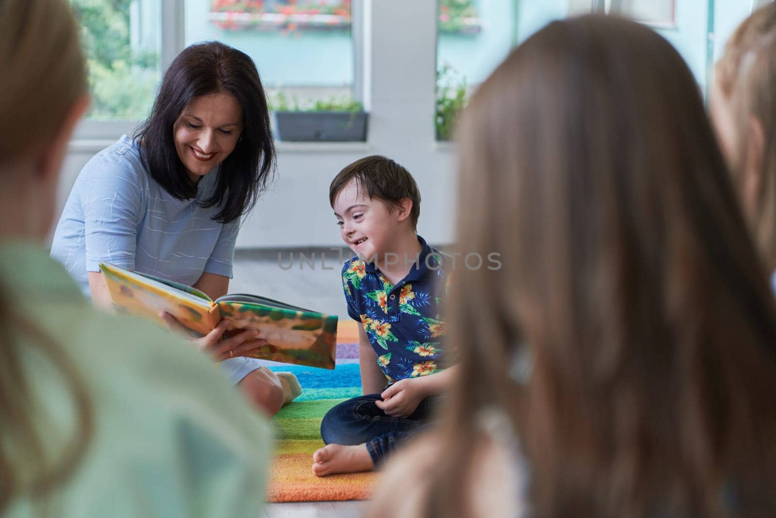 Reading time in an elementary school or kindergarten, a teacher reading a book to children in an elementary school or kindergarten. The concept of pre-school education. Selective focus by dotshock