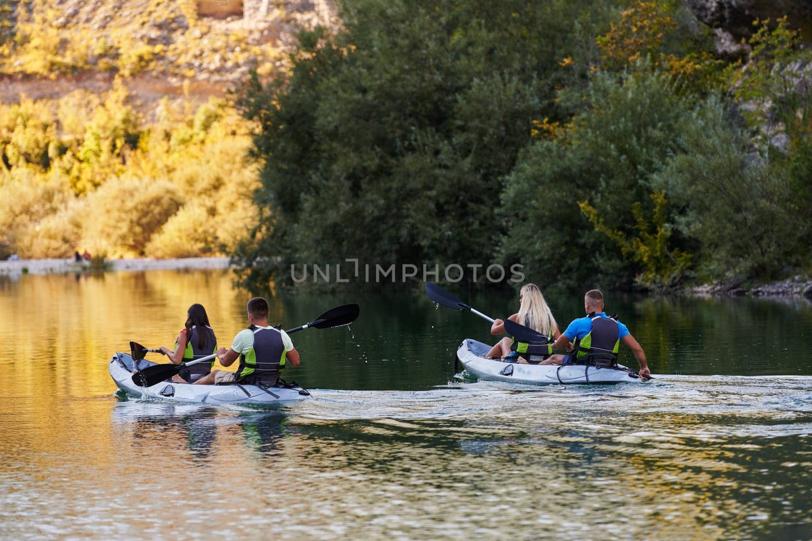 A group of friends enjoying having fun and kayaking while exploring the calm river, surrounding forest and large natural river canyons by dotshock