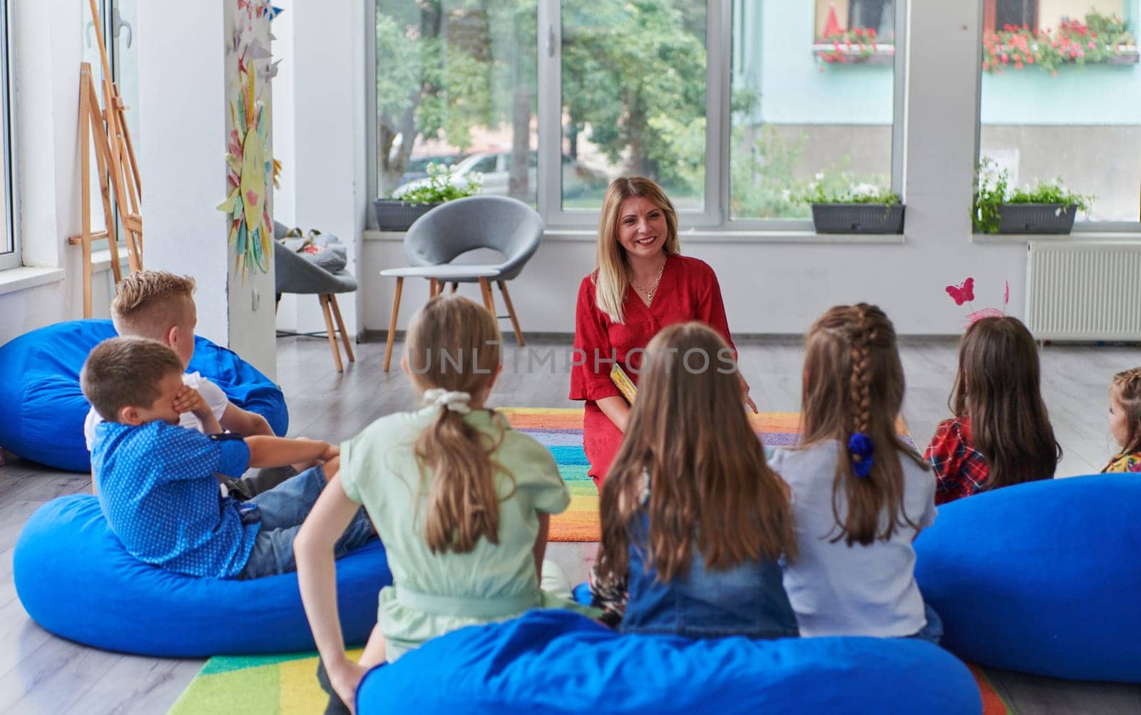 Reading time in an elementary school or kindergarten, a teacher reading a book to children in an elementary school or kindergarten. The concept of pre-school education. Selective focus by dotshock