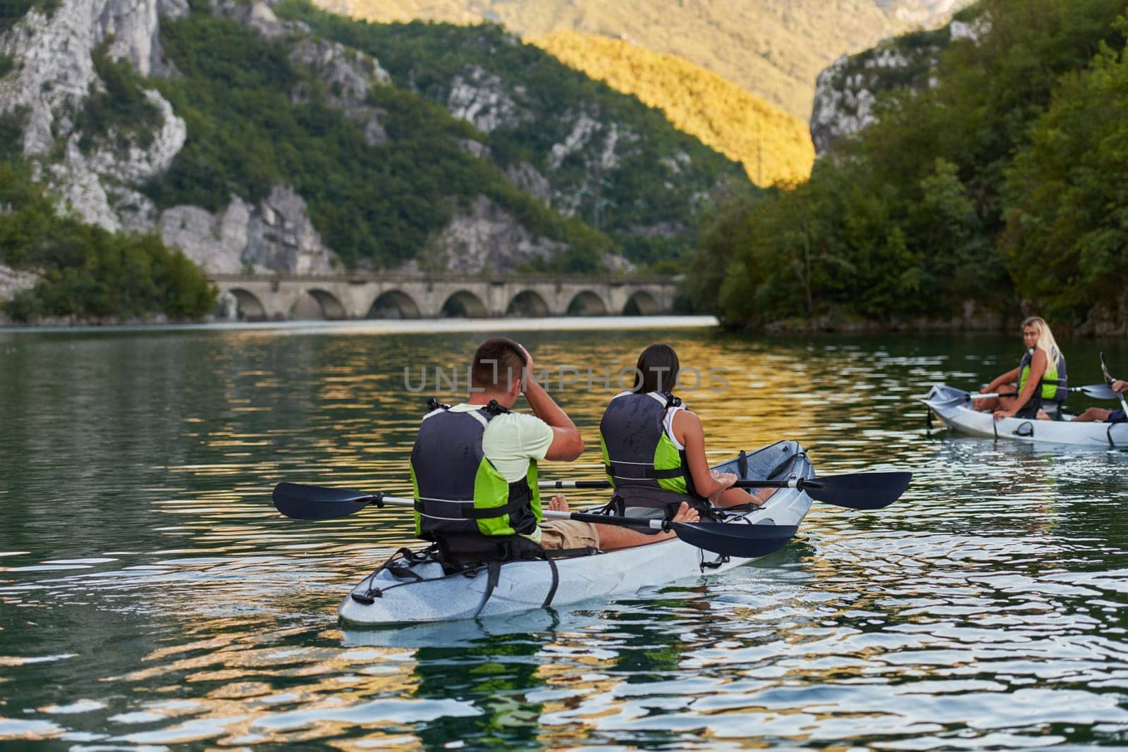 A group of friends enjoying having fun and kayaking while exploring the calm river, surrounding forest and large natural river canyons.