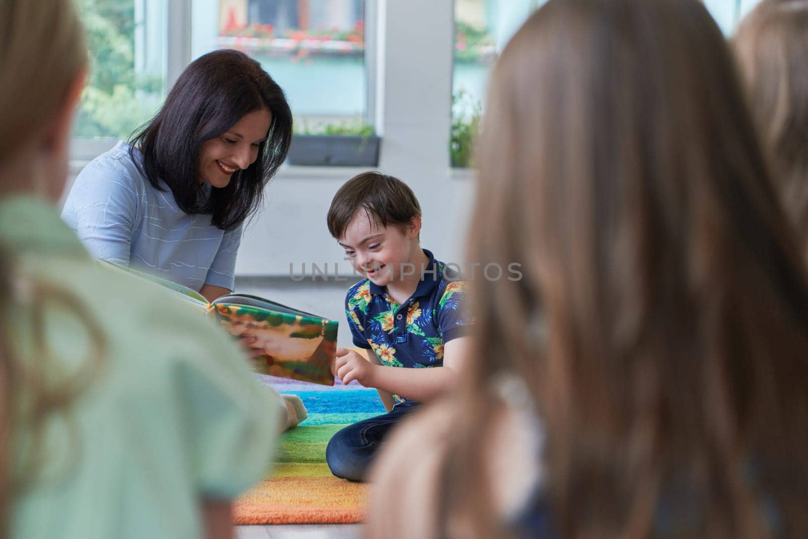 Reading time in an elementary school or kindergarten, a teacher reading a book to children in an elementary school or kindergarten. The concept of pre-school education. Selective focus by dotshock