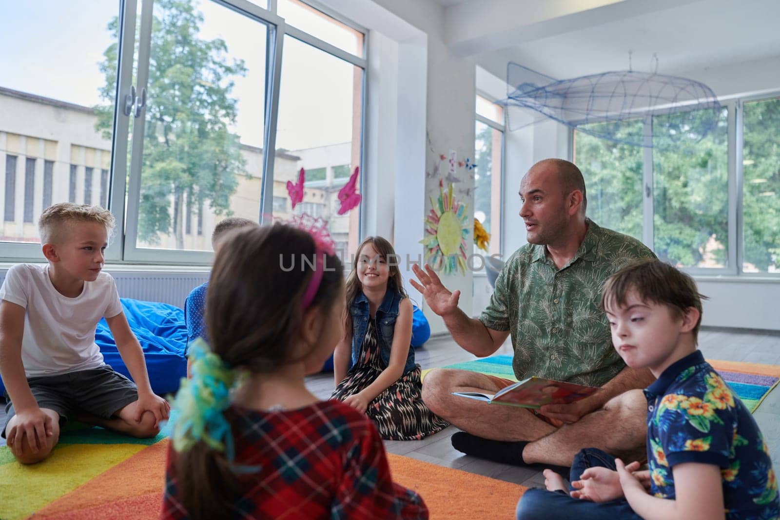 Reading time in an elementary school or kindergarten, a teacher reading a book to children in an elementary school or kindergarten. The concept of pre-school education. Selective focus by dotshock