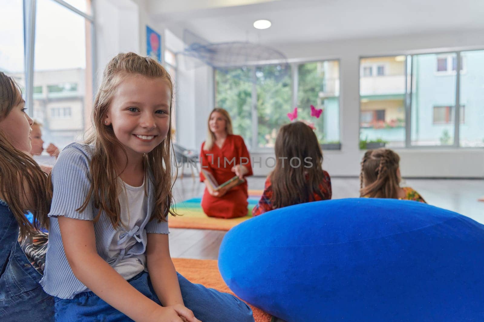 Reading time in an elementary school or kindergarten, a teacher reading a book to children in an elementary school or kindergarten. The concept of pre-school education. Selective focus by dotshock