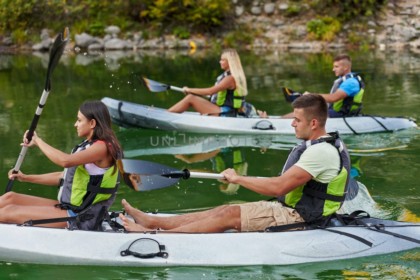 A group of friends enjoying having fun and kayaking while exploring the calm river, surrounding forest and large natural river canyons by dotshock