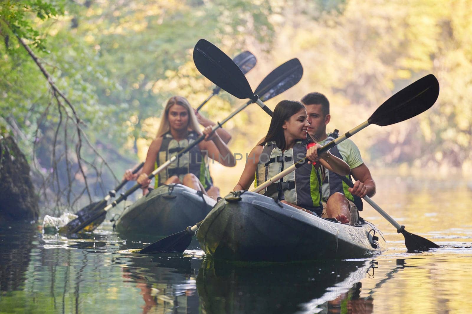 A group of friends enjoying having fun and kayaking while exploring the calm river, surrounding forest and large natural river canyons by dotshock